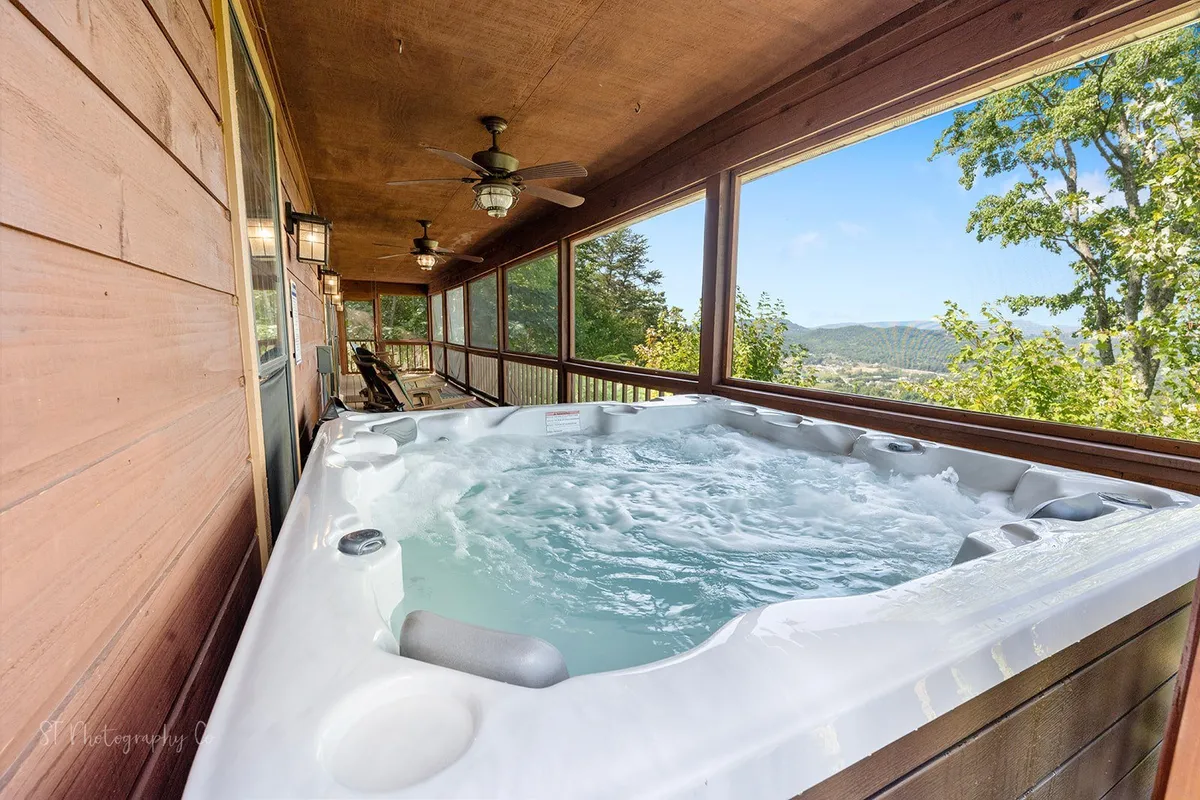 A serene outdoor hot tub overlooks surrounding nature and distant mountain views, offering a tranquil space for relaxation. The scene evokes the rejuvenation possible after a fun-filled day exploring attractions or hiking the Smokies.