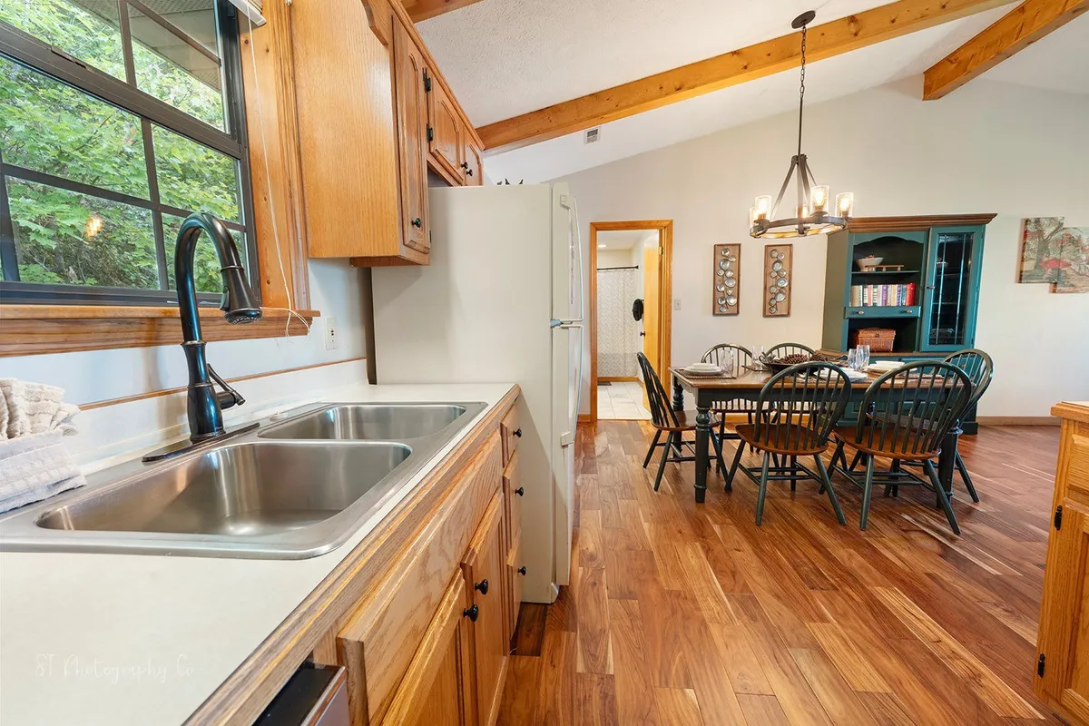 A warm and welcoming kitchen and dining space with exposed wooden beams, a bright kitchen sink, and a large table ready for dining or socializing. The ambiance encourages relaxation and connection after a day of local adventures.
