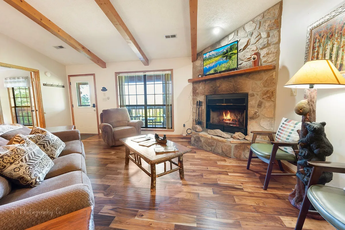 A cozy living room featuring a welcoming fireplace, a plush sofa, a coffee table, and a TV, all arranged in an open, inviting space. The furniture layout encourages relaxation, socializing, and family activities, with ample room for everyone, including pets, to unwind comfortably.