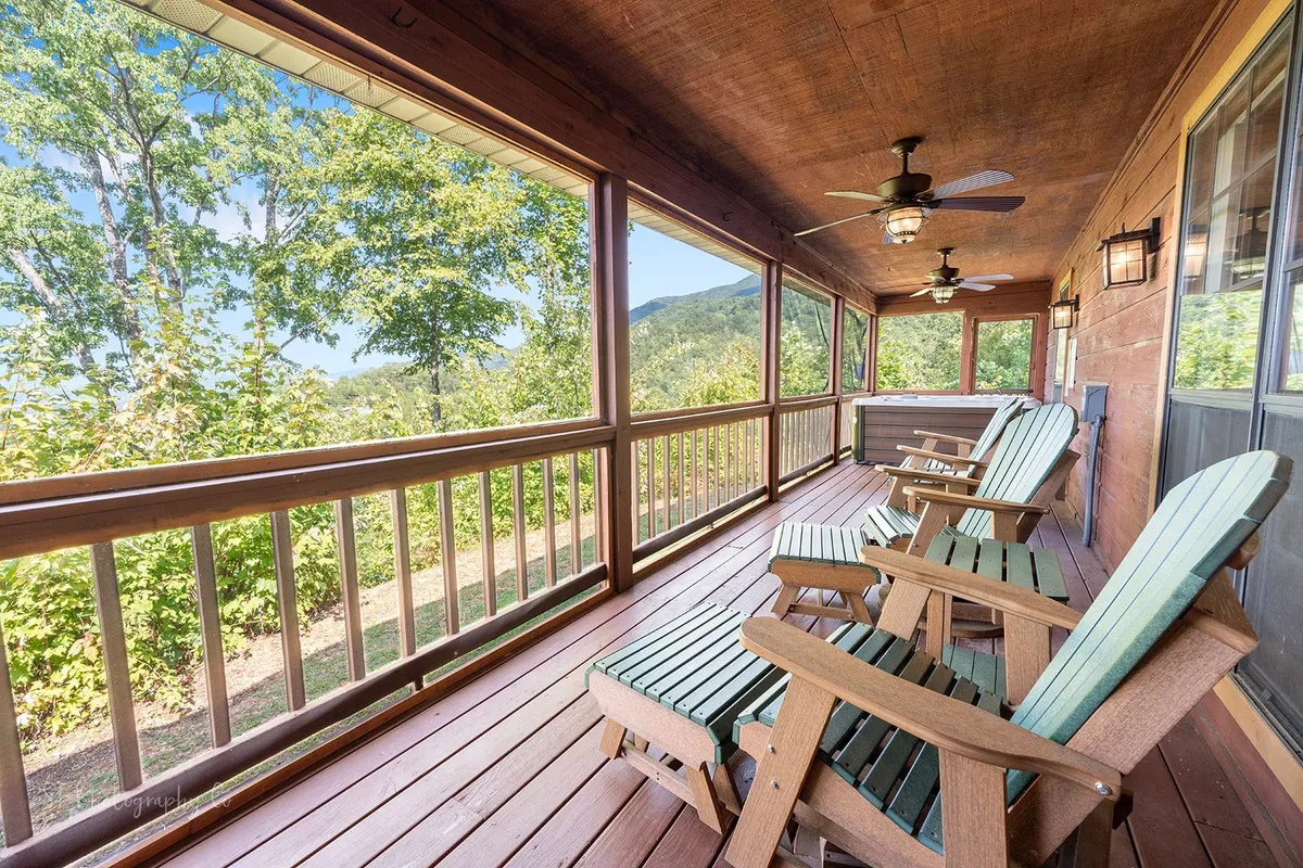 A spacious wooden deck features rustic rocking chairs facing a sweeping vista of mountains and open sky. The natural wood elements of the deck complement the lush, scenic backdrop, providing an inviting spot for morning sunrises or stargazing at night.