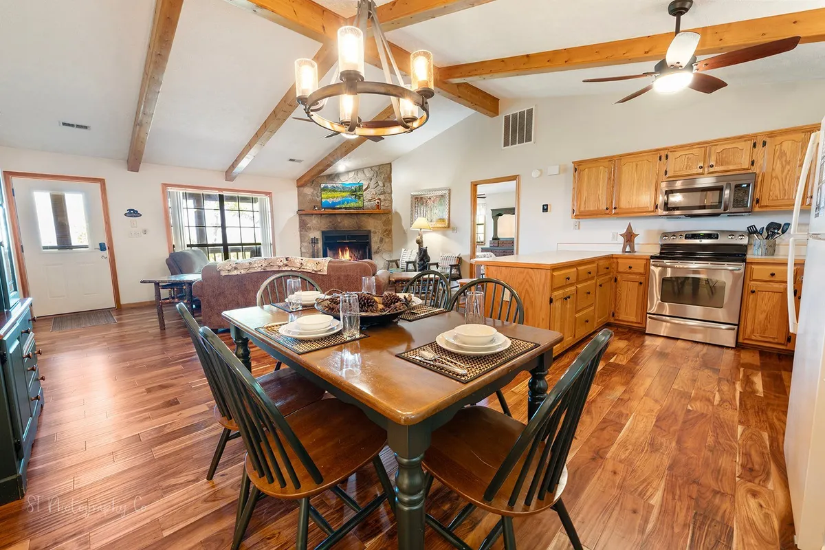 A welcoming dining area with a set table, wooden cabinetry, and a stone fireplace in the background. The scene is set for family meals, casual gatherings, and shared moments, emphasizing warmth, comfort, and togetherness.