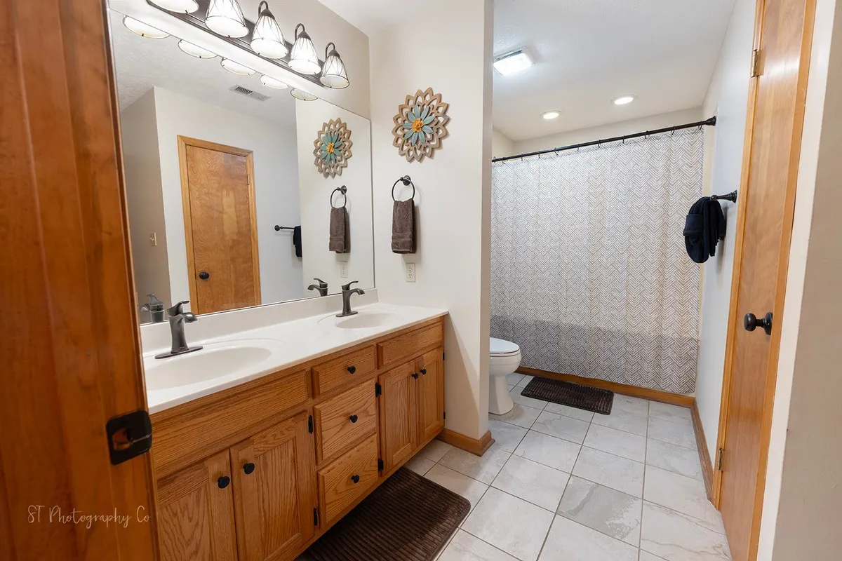 A spacious en-suite bathroom with a double sink vanity, decorative mirrors, and a shower curtain. The space feels calm, organized, and is designed for relaxation and convenience—perfect for starting or ending your day in comfort.